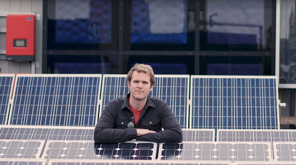 Man on a roof top with solar cells.