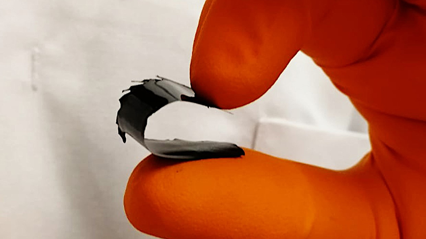 ​ Hand som håller en bit material målat med den termoelektriska färgen.