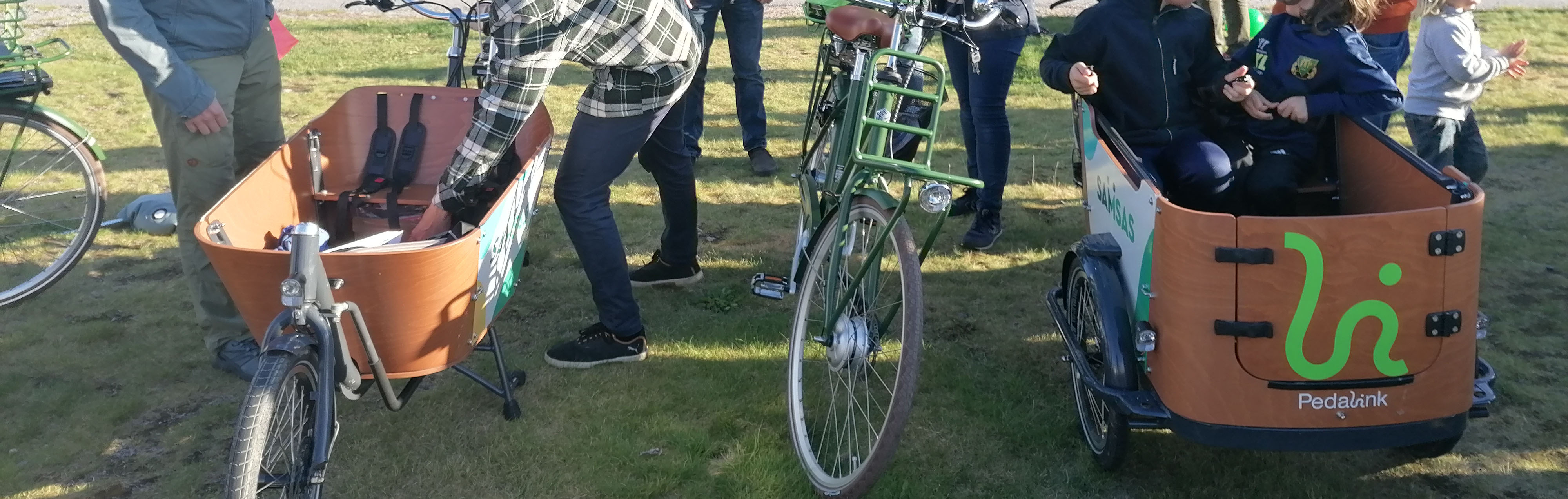 Ett dussin personer tittar på lådcyklar