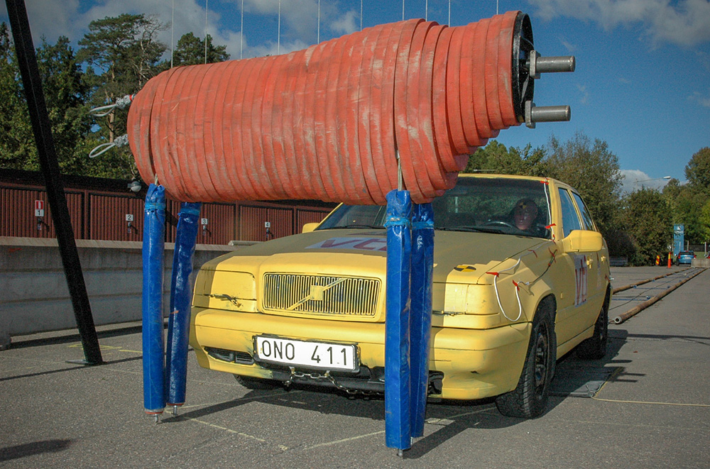  En krockdocka i form av en älg i naturlig storlek placerad framför fronten på en personbil.