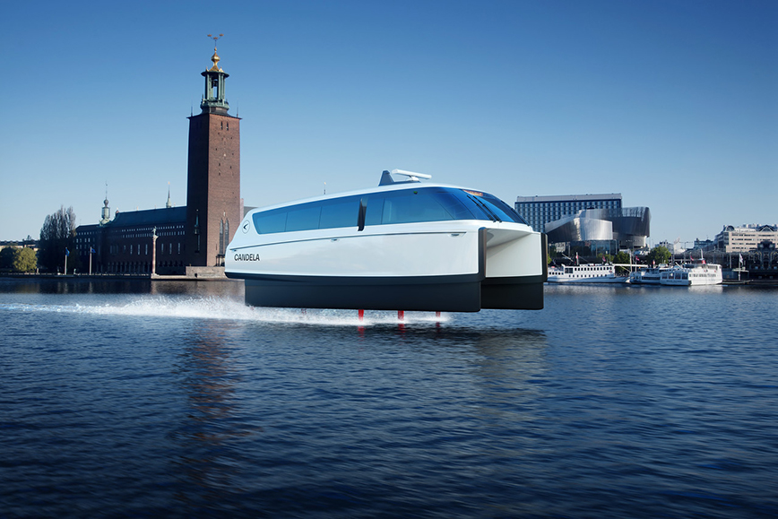 An electric hydrofoil boat in motion in Lake Mälaren in front of Stockholm City Hall.