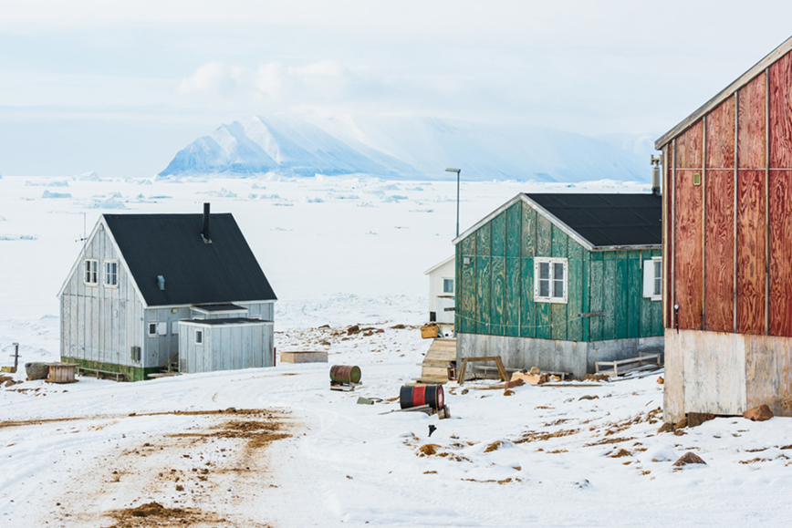 Tre bostadshus i arktisk miljö med snö.