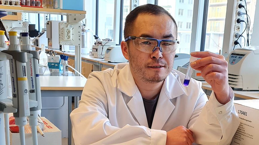 KTH-forskaren Hongji Yan håller i ett provrör med blå vätska i