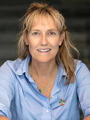 Porträttfoto: en blond leende kvinna i ljusblå skjorta.