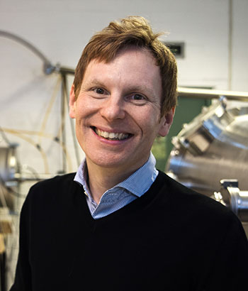 Portrait photo: A smiling man wearing a dark sweater. 