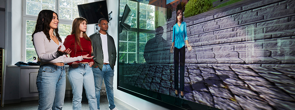 Tre studenter interagerar med en avatar i VIC-studion på KTH Campus.