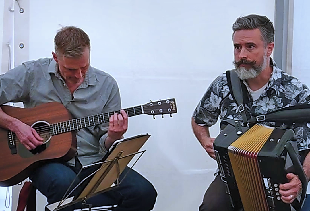 two musicians play guitar and accordion.