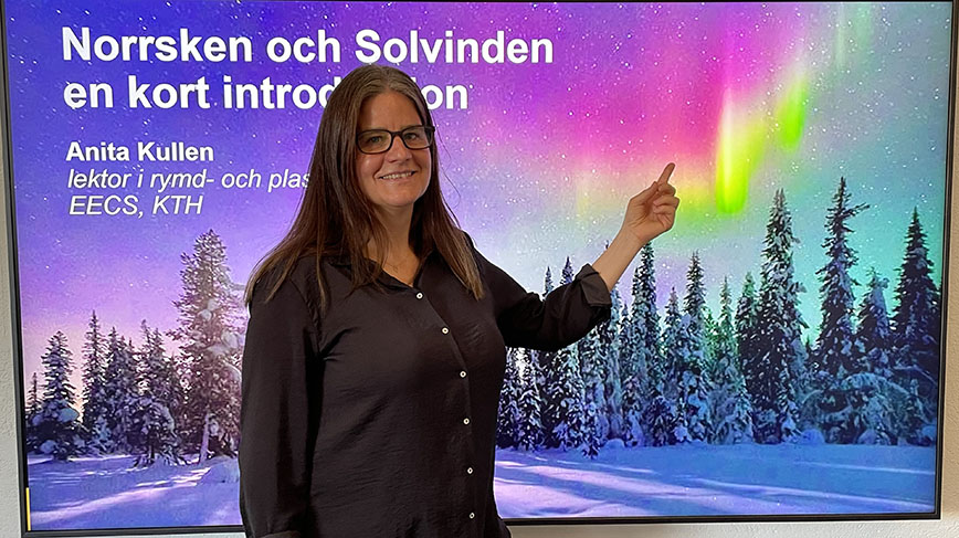 Anita Kullen står framför en bild på norrsken