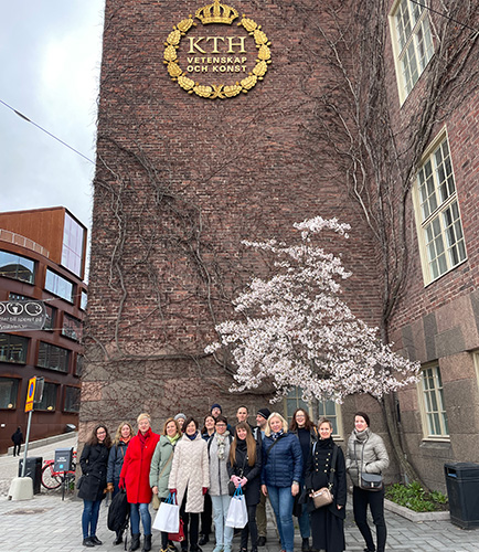a group of people standing under KTH's emblem