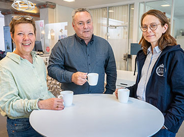 Marie Larsson, Hans Wohlfarth och Charlotta Andresson Lund med koppar runt ett bord.