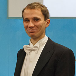 A man with short dark blonde hair and wearing a tuxedo.