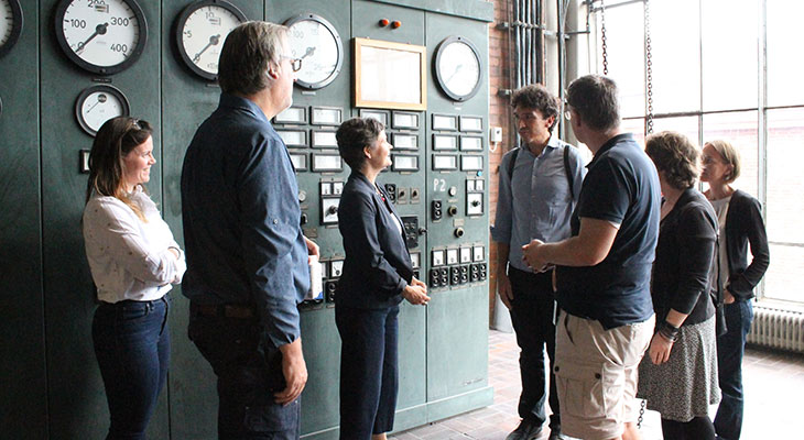 A group of people standing in front of an old control panel.