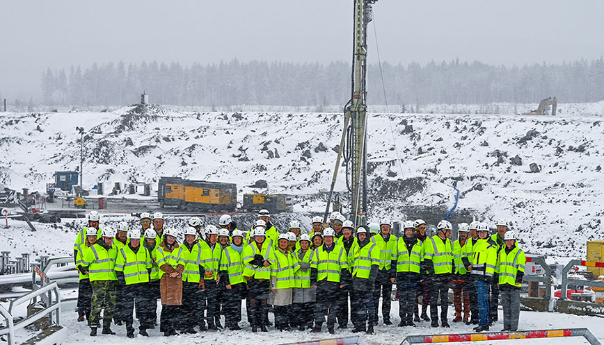 A group of people outside with helmets and reflective vests.