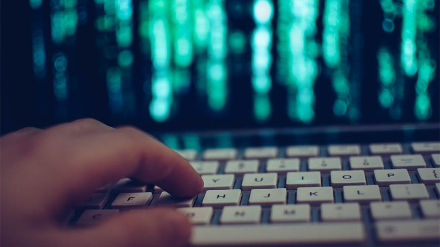 Hand on keyboard in front of computer screen