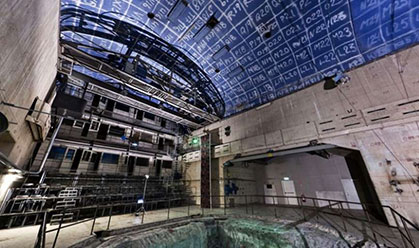 A large room with a concrete pit that is green and blue walls with white scriptures.