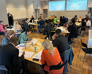 Several groups of people looking at the presentation and working together