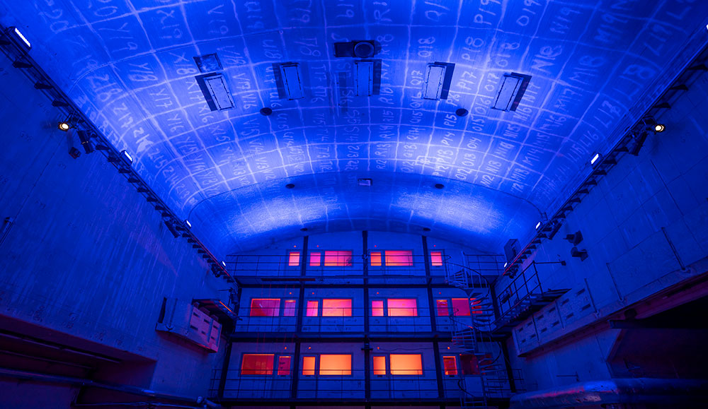 A big venue that is lit up in blue and with windows lit up in red and organge,