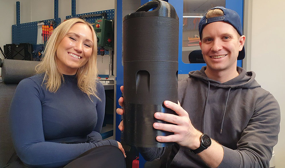 En kvinna och en man där mannen håller upp en cylinderformad apparat