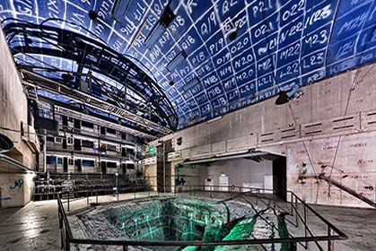 A big venue with blue ceiling with white signs and a green concrete pit.