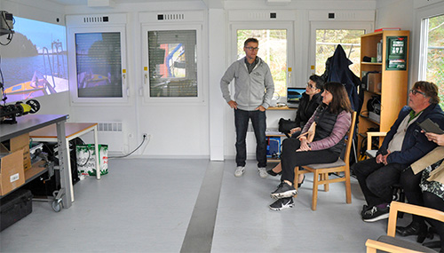A man talking to a slide in front of a small audience