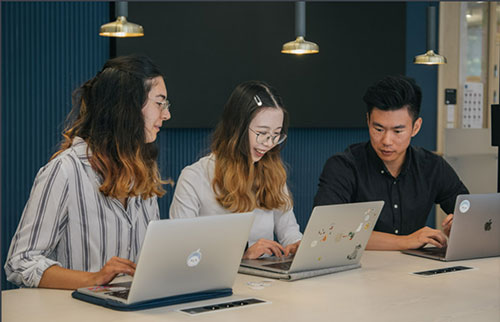 Tre personer interagerar framför tre bärbara datorer.