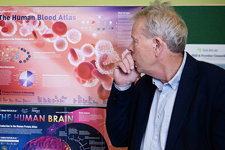 A man in front of a poster with proteins.