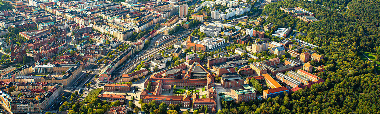 A aerial photo of a large buiilding with surrounding buildings and greenery..