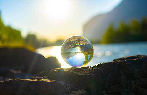 A glass globe in front of water and nature.