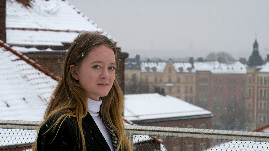 Student stående på en balkong i vintermiljö.