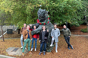 People posing by a bear statue
