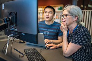 Researcher and librarian sitting in front of a screen discussing.