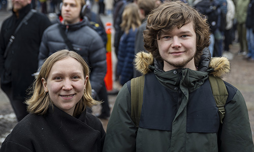 Two åersons standing in a long queue at KTH Campus.
