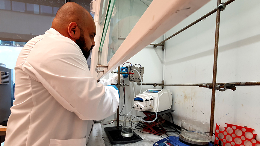 man in white lab coat working on machine in lab