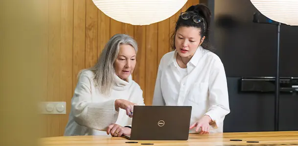Två yrkesverksamma studenter tittar på en laptop tillsammans.