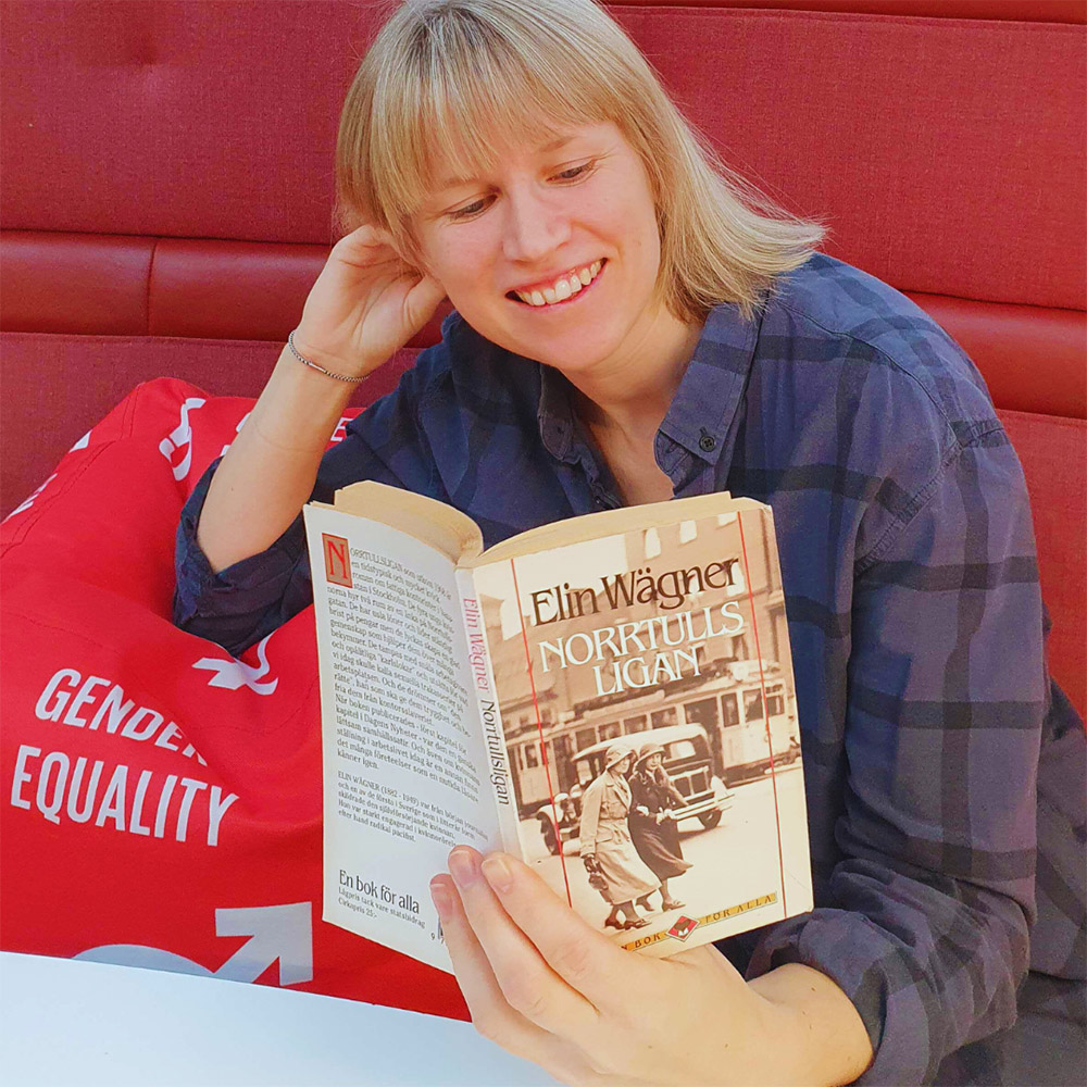 Librarian leaning on pillow with the text gender equality, reading a book