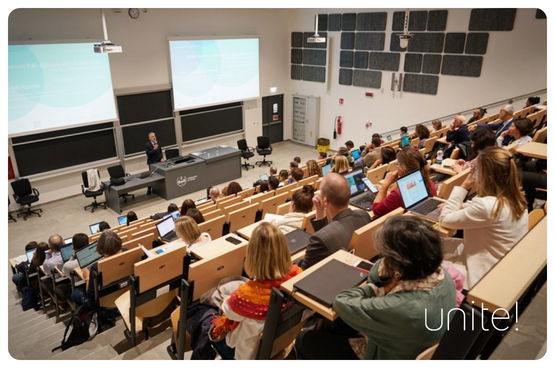 A group of people listening to a lecturer in a lecture hall