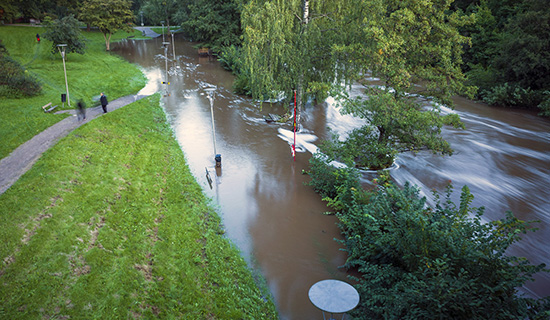 En översvämmad flod med några personer som promenerar strax intill