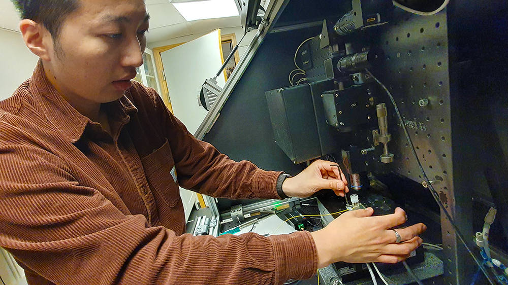 Researcher Lee-Lun Lai adjusting laser pointer on 3D printing machine