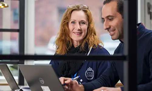 Two smiling people in front of a computer.
