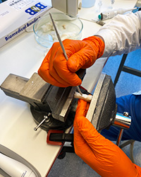 Närbild på händer som skulpterar Biomedical Bondings material med hjälp av en spatel.