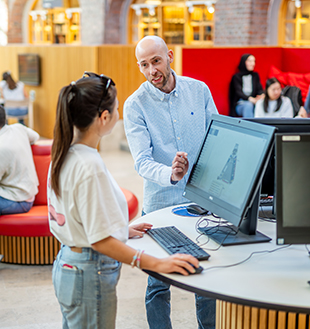 Bibliotekarie hjälper student vid datorer