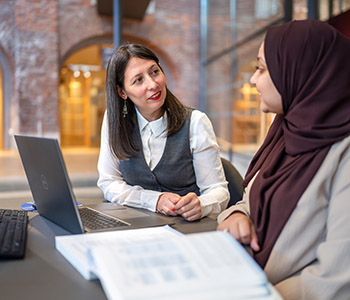 Librarian and student smile to each other in front of a computer. 