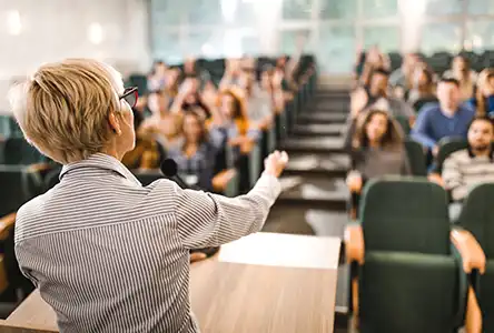 Lärare sedd bakifrån i en gradängsal med studenter.