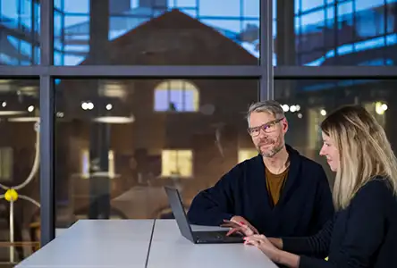 En man och en kvinna framför en dator. Ser ut att arbeta tillsammans.