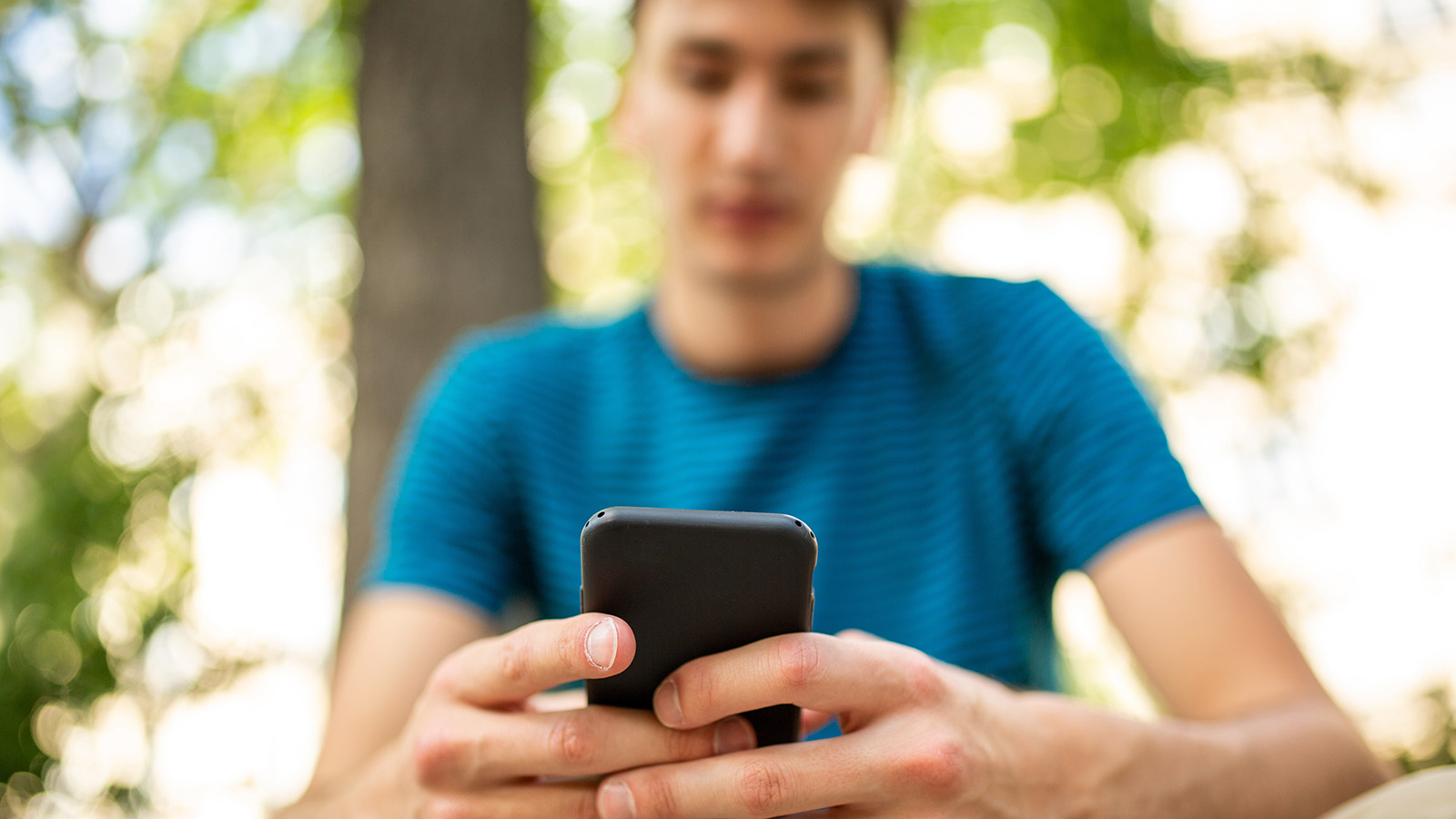 Young person using mobile phone in outdoor environment