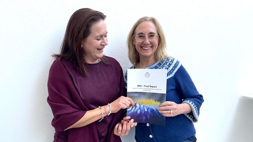 Two women with a report in their hands, smiling to the camera.