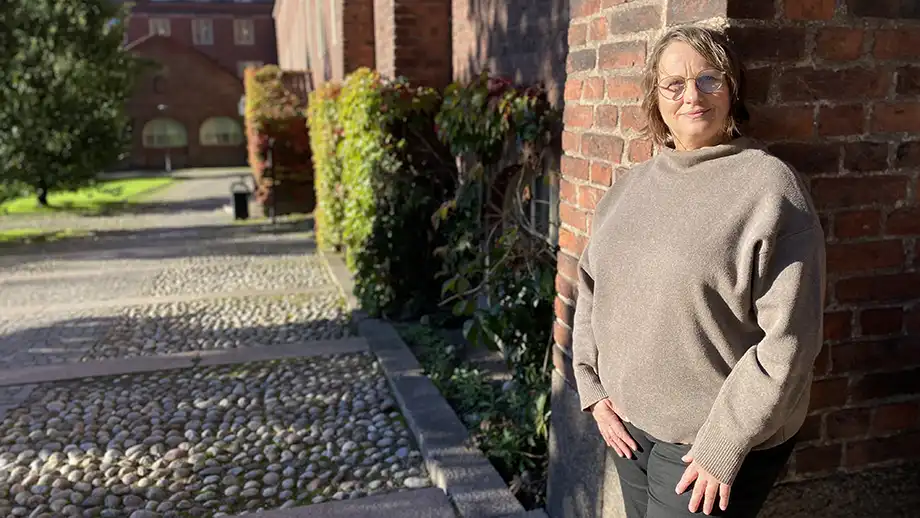 Woman standing against a brick wall.