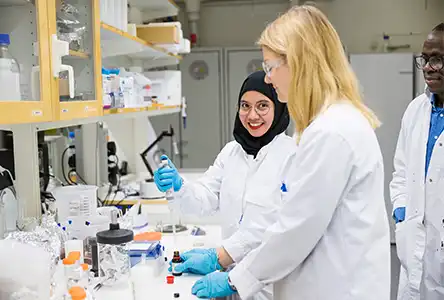 Tre personer i ett laboratorium med vita labbrockar.
