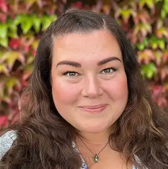 Portrait photo of a woman in front of a background of red and green leaves.