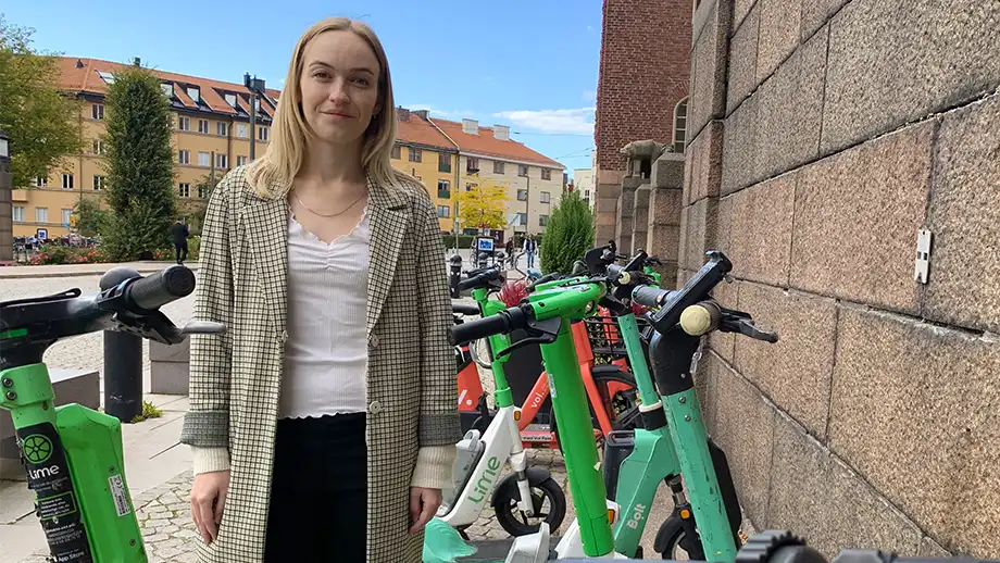 woman standing amid parked scooters